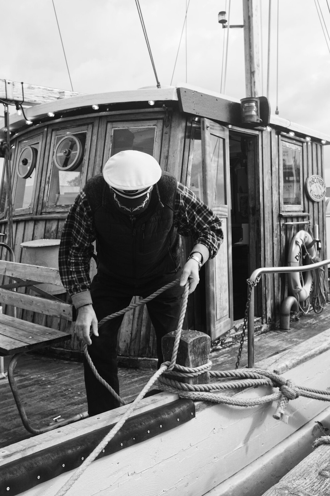 Fisherman mending nets on a wooden boat at a coastal port