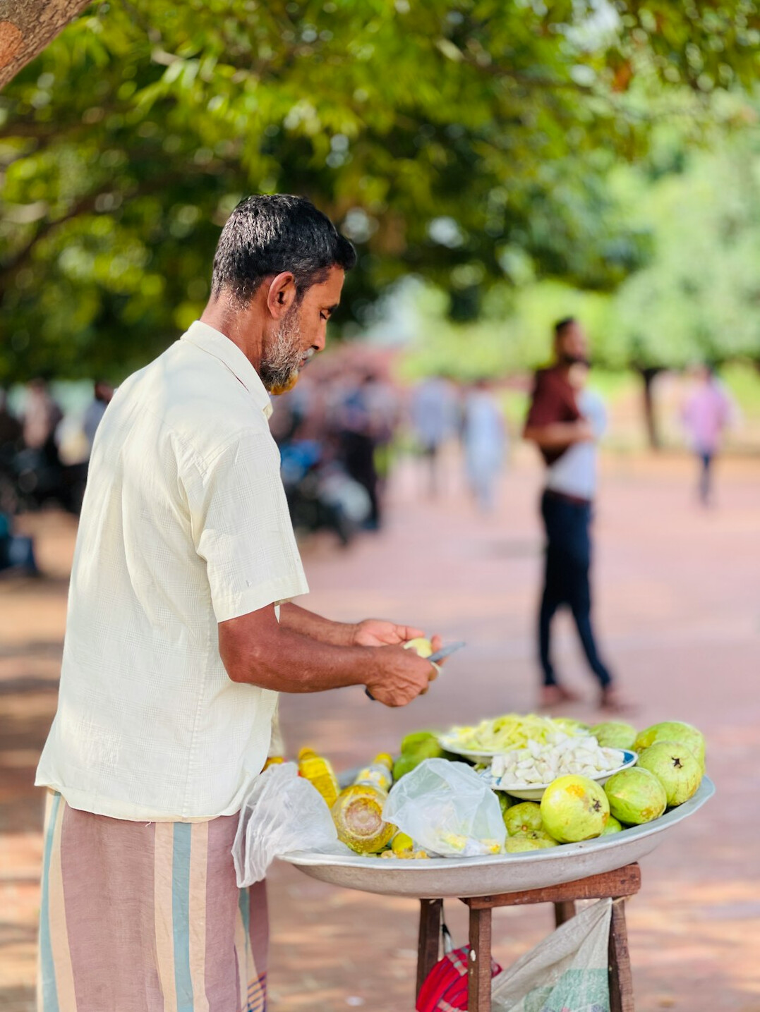 Vendor arranging fresh fruit at an outdoor market stall